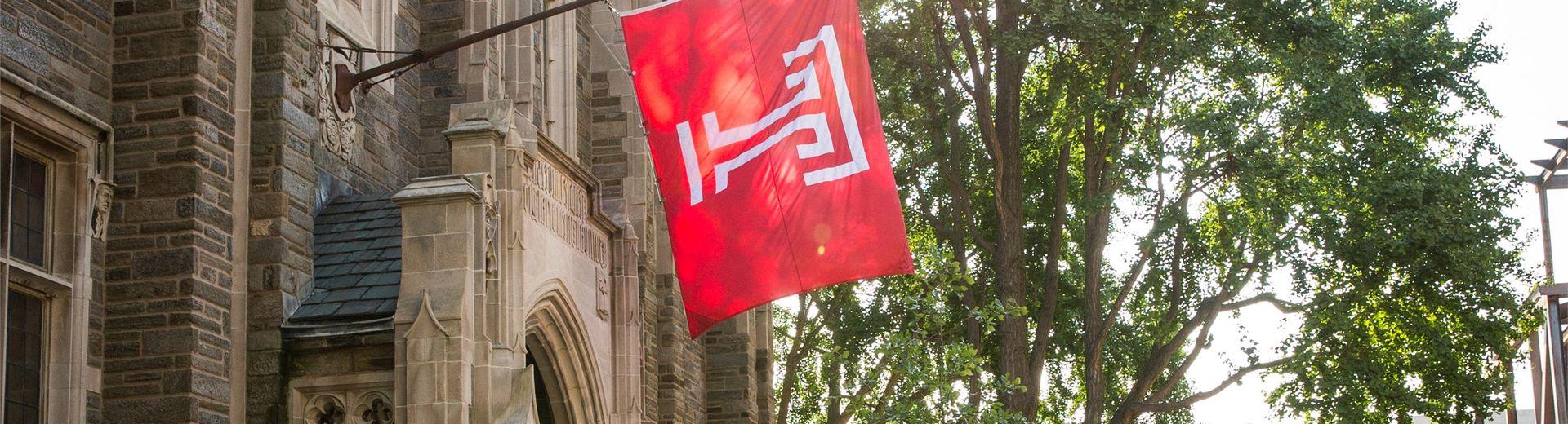 Temple University flag hangs from a historic building on campus.